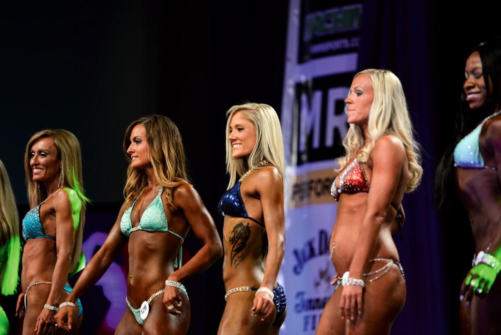 Crestwood junior Allie Boon, middle, waits to receive her sword after winning first place in the novice bikini competition. Boon also received a second-place award in the collegiate division.